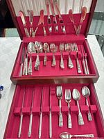 Full flatware set in open wood case showing two tiers of pieces