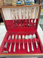 Open wooden chest showing full 46-piece flatware set