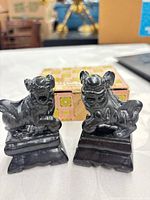 front view of two black stone carved dog figurines
