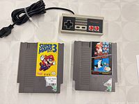 NES controller with cord and two NES game cartridges laid out