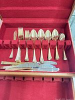 Open chest showing assorted gold-plated flatware pieces