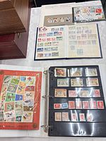 Overall view of four stamp items: Canada Post book, small blue album open, red World Cup sheet, black binder album