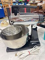 Side view of Sunbeam Mixmaster on base with large stainless bowl, smaller bowl nested, beaters and cord visible