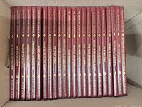 Box containing 24 burgundy hardcover books with gilt spine titles