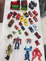 Overview of trains, die-cast cars and action figures laid out on surface