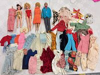 Group shot of four dolls and extensive array of clothing pieces