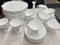 Stack of oblong snack plates, footed punch cups, handled teacups and saucers
