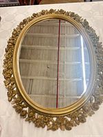 Full view of oval mirror with gold floral frame