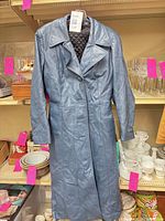Front view of blue trench coat hanging, buttons closed