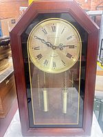 Front view of wood-cased wall clock showing dial and weights