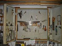 View of the main cabinet door and side doors, showing an assortment of saws, hand tools, and pliers attached to the doors.