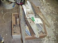 Wooden crate filled with various metal hinges of different sizes and some rusted