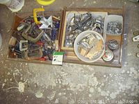 Wooden boxes on floor containing a variety of metal clamps including C clamps, F clamps, along with additional hardware items