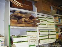 Storage cabinet with labeled bins containing various hardware items and wood pieces on top shelf.