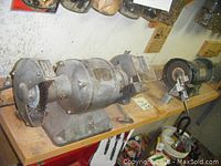 Hercules electric grinder with steel brush and grindstone on workbench next to other grinder and vice