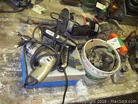 Overall view of hot glue gun box, drill, router and planer piled on table