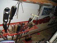 Wall-mounted rack holding 12 assorted screwdrivers and 2 chisels mounted on red plastic holder