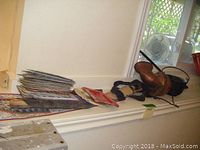 Photo showing a stack of old motorcycle license plates, brass horn, and leather sheathed knives.