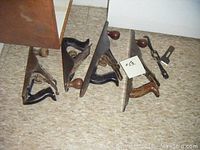 Group of five metal-bodied hand planes arranged in two rows on floor