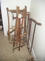 Group view of four wooden saw frames and one axe leaning against wall