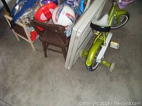 Overall view of bike, chairs, doll bed, and balls arranged on concrete floor