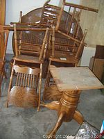 Photo showing the upside down table and multiple chairs stacked, highlighting the pedestal base and claw feet detail of the table.