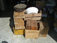 Lot overview showing four wooden crates, yellow crate, cast iron pot on top of left crate, and enamel wash bin inside crate