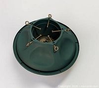 Top view of green plastic Christmas tree stand showing eye-bolt screws and metal center plate