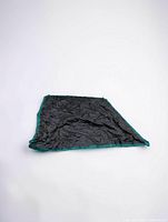 Tarp laid flat on white backdrop showing black center and green border