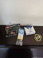 All four items arranged on surface: LEGO polybag, Brick Loot LED kit, sealed Miffy box, Hufflepuff patch