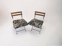 Two black metal folding chairs with floral cushions facing camera