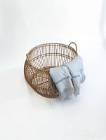 Angled view of round wicker basket with blanket for scale