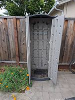 Cabinet outdoors, right door open showing interior grid back panel and metal bar