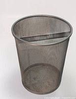 Side view of silver mesh metal cylindrical wastebasket showing rolled rim and mesh sides
