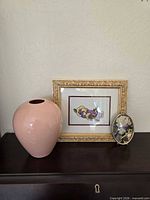 Overall view of vase, framed embroidery and shadow box