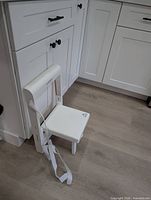 Stool mounted to kitchen cabinet with seat folded down showing use context