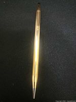 Full view of gold-plated Cross pencil on dark background