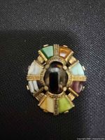 Front view of scarf ring showing multicolour inlays and central black cabochon