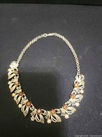 Full view of gold tone necklace showing decorative front links and rhinestones