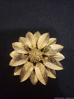 Front view of gold-tone flower brooch showing layered petals and center