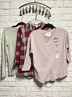 All three tops hanging: grey tee, plaid shirt, mauve tee