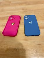 Pink and blue iPhone 16 silicone cases on wood surface