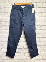 Front view of new navy chino pants hanging with tag visible