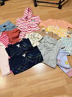 All sixteen baby garments spread on floor