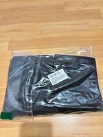 Sealed black postpartum belly wrap in clear plastic bag, barcode label visible