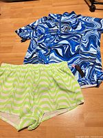 Rash guard top and swim shorts laid flat to show patterns, colors, size tag and new condition