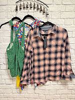 Three tops on hangers against brick wall