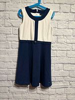 Front view of navy and white sleeveless dress on hanger
