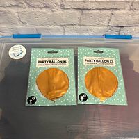 Front view of two sealed Party Balloon XL packages showing gold balloon graphics