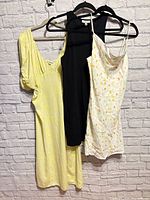 Three Nordstrom women’s dresses on hangers against brick wall